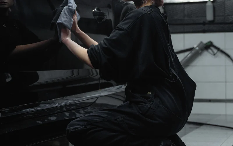 Hands using a microfibre cloth to care for dark bodywork.